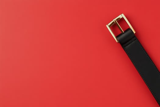 Black leather belt on a solid red background showcasing classic style and elegance in accessories photo