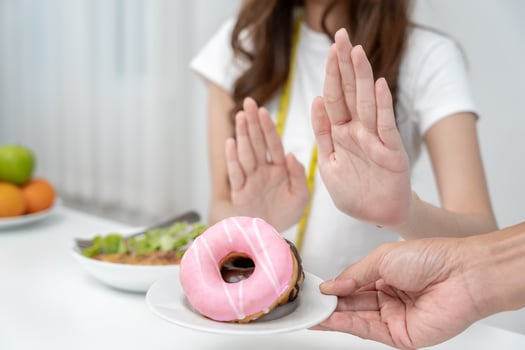 Diet and dieting. Beauty slim female body confuse donut. Woman in exercise clothes achieves weight loss goal for healthy life, crazy about thinness, thin waist, nutritionist. photo