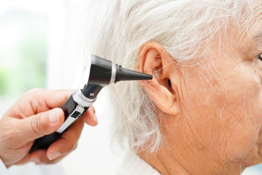 Otolaryngologist or ENT physician doctor examining senior patient ear with otoscope, hearing loss problem. photo