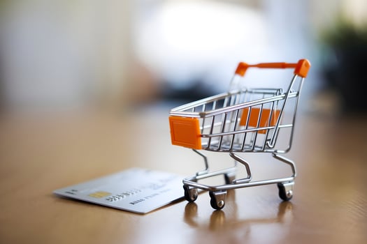 Mini shopping cart beside credit card, metallic contrast draws focused attention photo