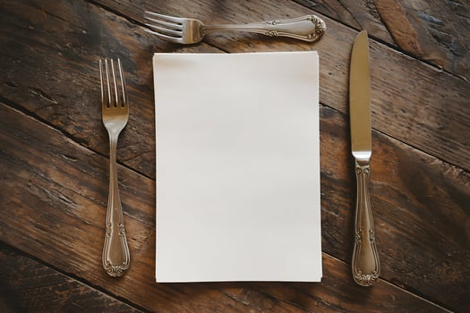 A blank paper lies neatly on a rustic wooden table with silverware photo