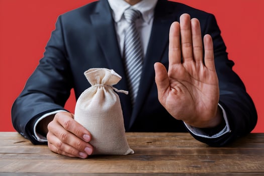 Suited man holds coin sack, gestures stop, bold red backdrop photo