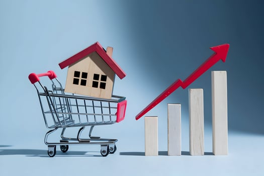 Mini shopping cart cradles wooden house, red arrow symbolizes housing growth photo