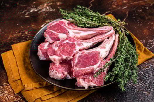 Raw lamb chops, fresh mutton meat cutlets on a ribs. Dark background. Top view photo
