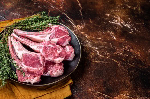 Raw lamb chops, fresh mutton meat cutlets on a ribs. Dark background. Top view. Copy space photo
