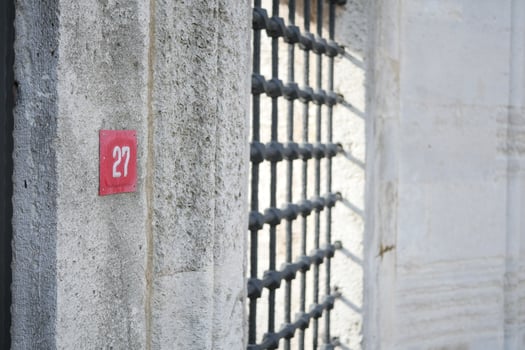 A Numbered Jail Cell Door Featuring Sturdy Metal Bars and a Concrete Wall photo
