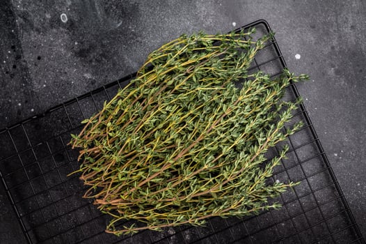 Fresh Herb thyme, sprigs bunch on a rack. black background. top view photo