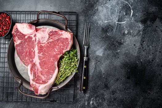 Fresh raw T-bone marbled beef meat Steak on a steel tray. Black background. Top view. Copy space photo
