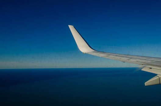 Airplane Wing Against a Clear Blue Sky and Sea Horizon photo