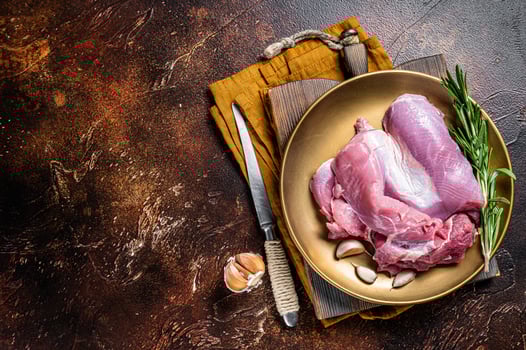 Fresh skinless raw Turkey thigh fillet meat with spices. Dark background. Top view. Space for text photo