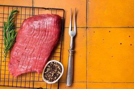 Raw flank beef meat steak ready for grilling. Orange background. Top view. Copy space photo