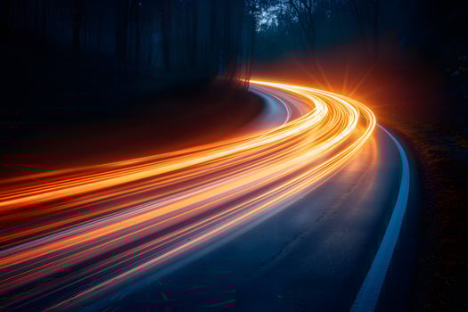 Long Exposure of Car Light Trails on a Curving Forest Road at Night photo
