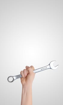 Hand holding a wrench raised high against a gray background, vertical composition with free space for promotional text, ideal for tool branding or industrial concept photo