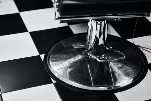 Barber chair on classic black and white checkered floor inside salon photo