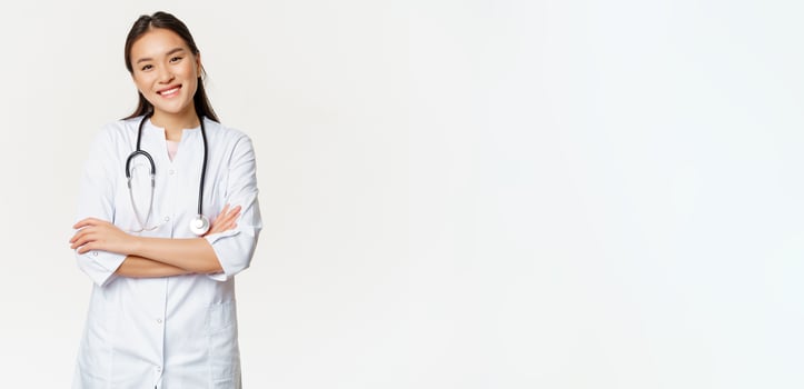 Asian female doctor, physician in medical uniform with stethoscope, cross arms on chest, smiling and looking like professional, white background photo
