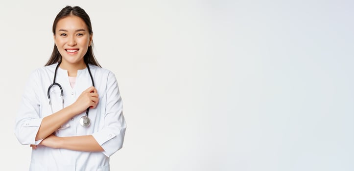 Healthcare and hospital concept. Smiling asian doctor, female nurse in uniform, looking happy at camera, standing over white background photo
