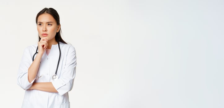 Image of serious doctor, female healthcare worker thinking, looking aside with concerned, frowning face expression, white background photo