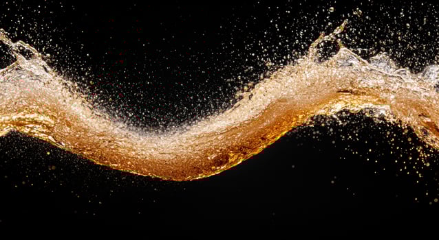 Splashing golden liquid against black background photo