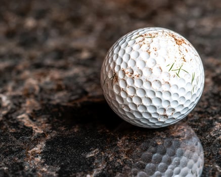Close up of a worn golf ball on a rocky surface photo
