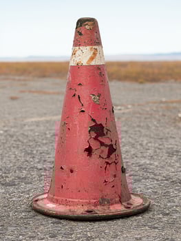 Weathered traffic cone on gravel road photo