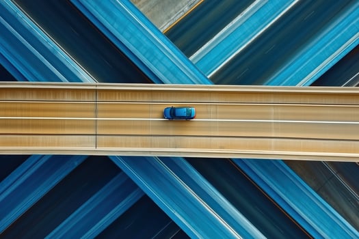 A sleek car glides over an intricate highway network captured from above, showcasing design and motion photo