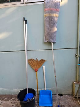 Home cleaning tools such as brooms, mops, water buckets, and dustpans. photo