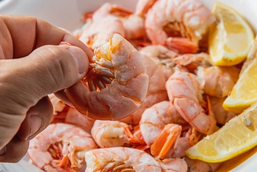 Tiger king prawns cooked and seasoned with lemon, close up in a man's fingers photo