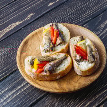fish sandwich with butter and sprats lemon and red pepper on a wooden plate photo