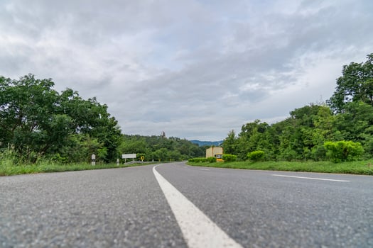 A ground-level perspective of a rural street in Tak Province, Thailand, in open sky during the day. This road serves as key transportation artery to western region of country. photo