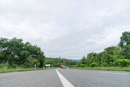 A ground-level perspective of a rural street in Tak Province, Thailand, in open sky during the day. This road serves as key transportation artery to western region of country. photo