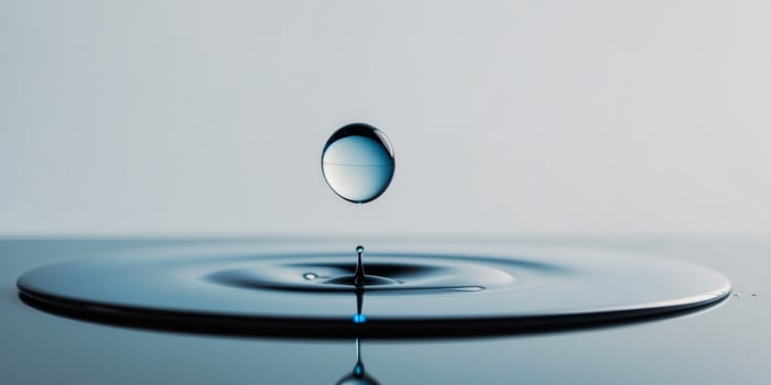 Elegant drop of water on smooth reflective surface with blue tones. photo