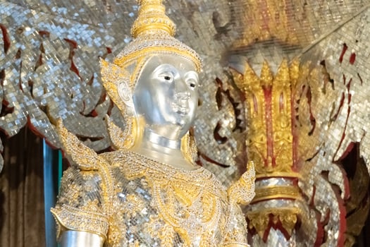 Deity statue standing straight made of silver, wearing silver gold costume with Chada on top of his head. Surrounded by sparkleling decoration. photo
