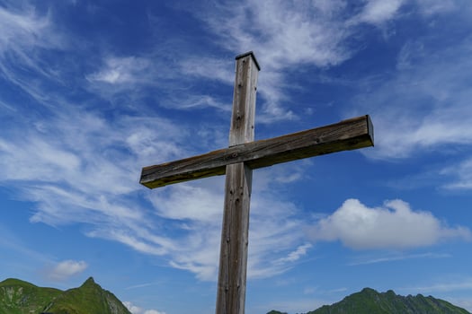 A wooden cross on a hillside with a blue sky photo
