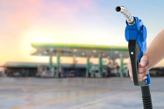 Holding a fuel nozzle against with gas station blurred background photo