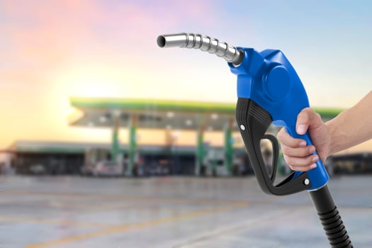 Holding a fuel nozzle against with gas station blurred background photo