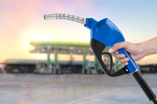 Holding a fuel nozzle against with gas station blurred background photo