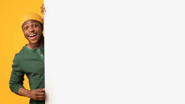 Cool Offer. Excited Funny Black Man Holding Blank White Advertisement Board, Cheerful African American Hipster Guy Demonstrating Big Placard With Free Copy Space For Your Design, Yellow Background photo