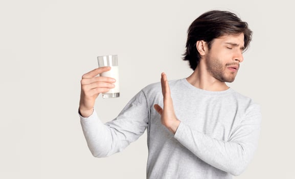 Food allergy concept. Man with dairy allergy and glass of milk photo