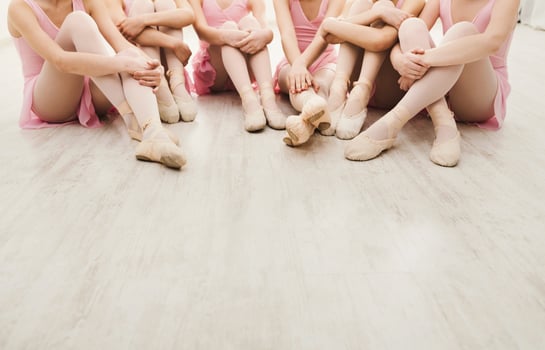 Little ballerinas talking in ballet studio. Group of girls having break in practice, sitting on floor, crop. Classical dance school photo