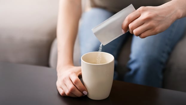 Infectious disease treatment. Unrecognizable woman pouring medication from package into cup indoors, closeup view photo