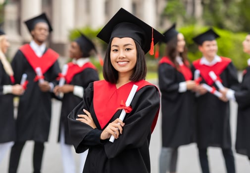 Happy young asian lady student having graduation party, wearing graduation costume and holding diploma, pretty female graduate proudly posing at university campus, blurred background photo