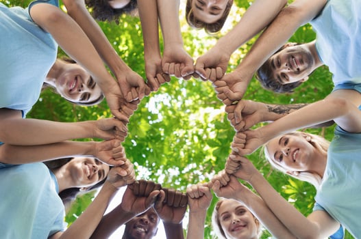Happy volunteers fist bump together, standing in park and making circle, unity and collaboration concept, copy space photo