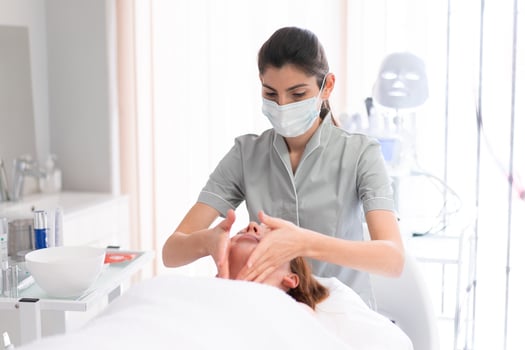 Female cosmetologist massaging relaxed woman's face at beauty salon photo
