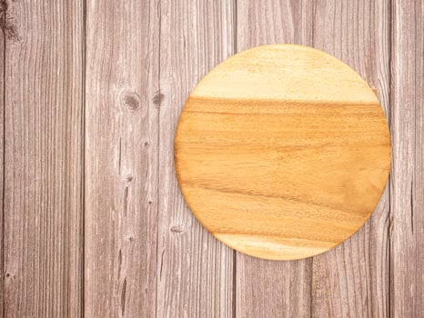 Top view of a blank round wooden cutting board over a wooden table photo