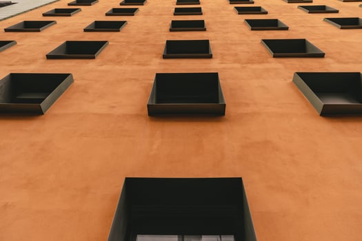 Contemporary building with terracotta color wall and rows of windows in metal frames. Modern architecture of Berlin Germany. Low angle view to facade exterior. Urban geometric pattern photo