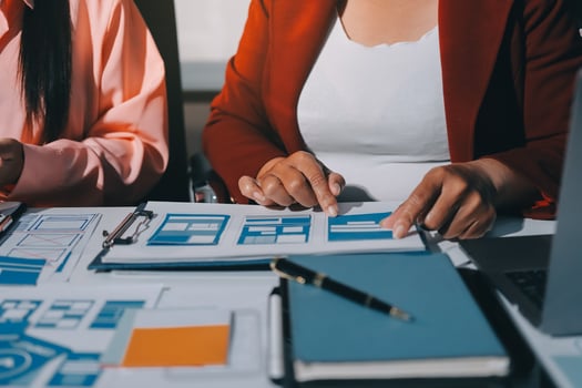 Two women working on a laptop and paper photo