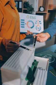 Two people are holding a model of a building photo