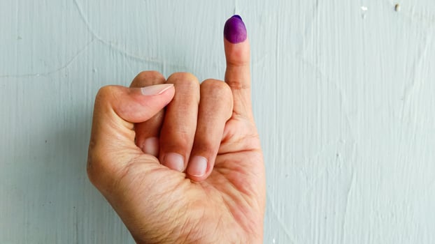 Hand with purple ink on the little finger, as a sign of having voted in the general election in Indonesia with isolated white background photo