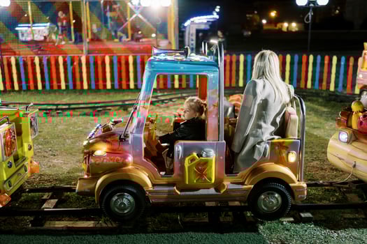 Little girl rides behind the wheel in a children train carriage at a fair photo