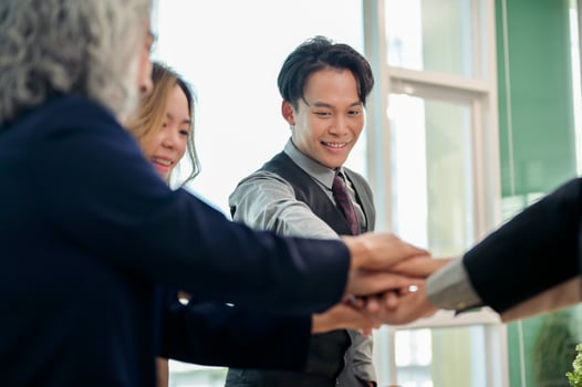 A close-up of businesspeople's hands coming together in a teamwork gesture, celebrating success. photo